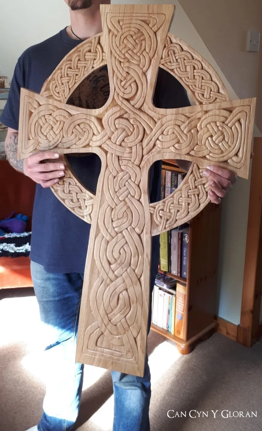 An oak carved Celtic cross of Saint Lawrence's church, replicated and held by Arwyn of Cân Cŷn y Gloran