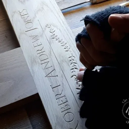 An oak memorial cross, the name and decorations being carved into it by Arwyn of Cân Cŷn y Gloran