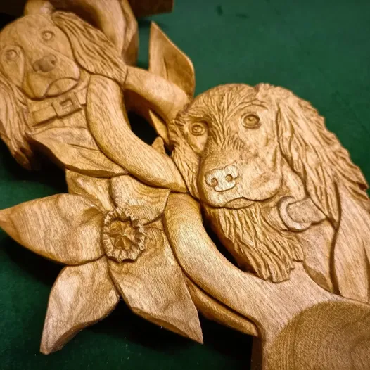 A cherry lovespoon, hand carved, depicting two cocker spaniels and a daffodil